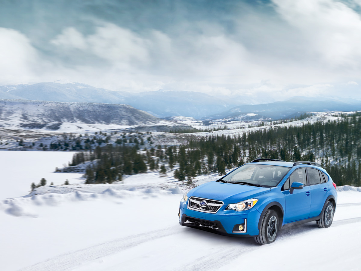 Retouched Subaru crosstrek blue SUV in snow with trees in background